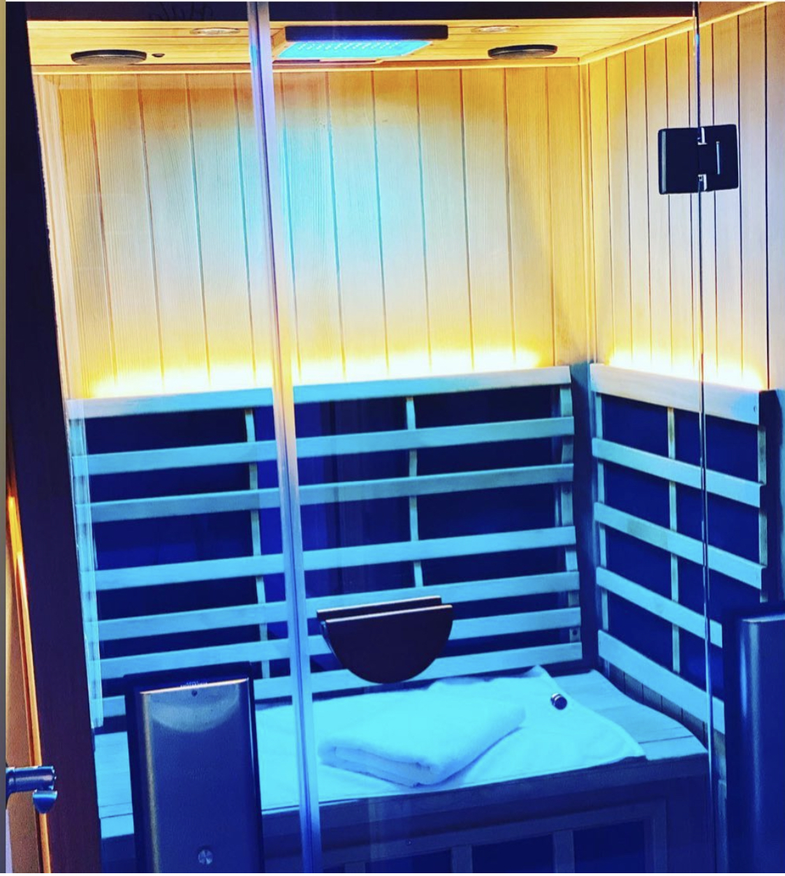 Infrared sauna room viewed through glass door with warm blue lighting