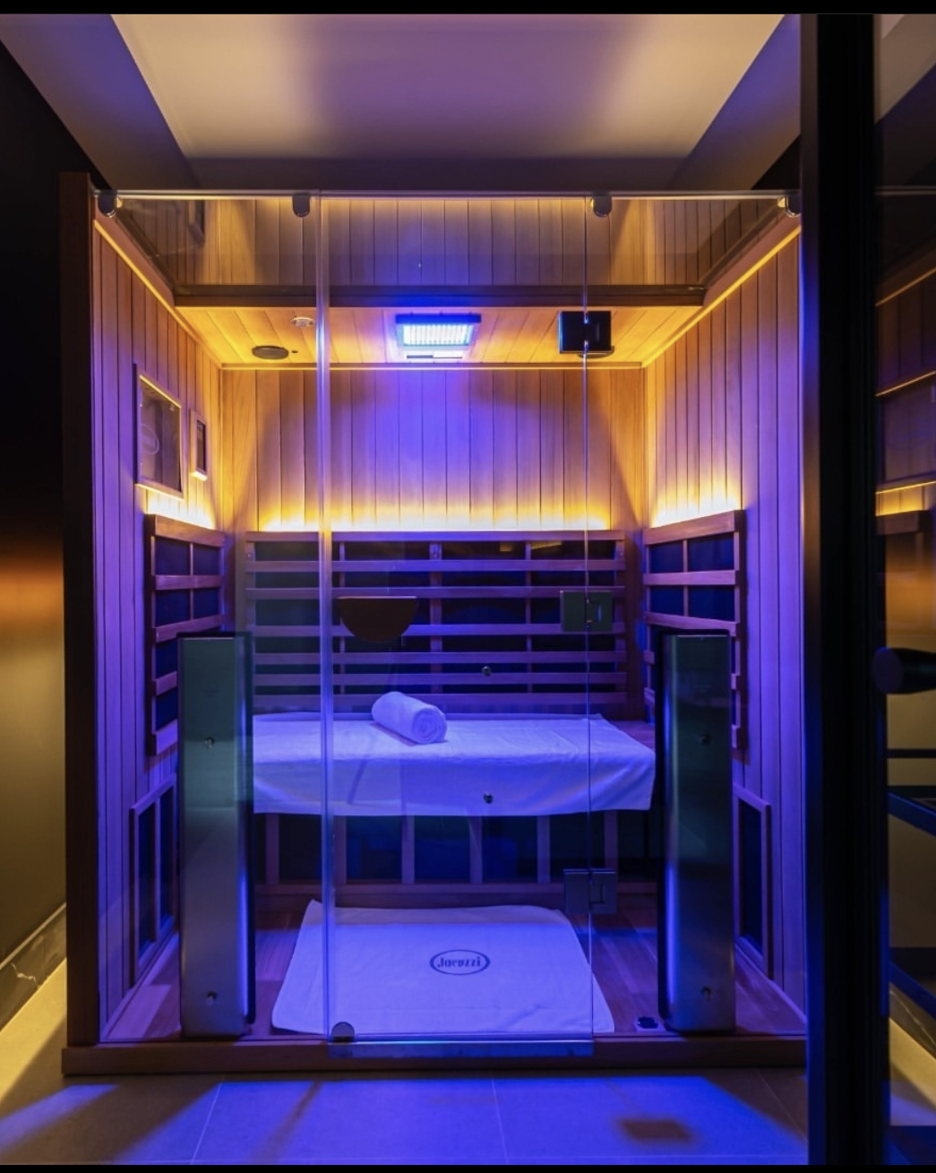 Clearlight infrared sauna with glass doors and blue-purple chromotherapy lighting