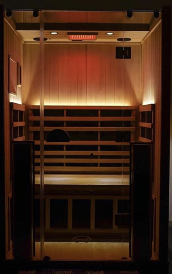 Infrared sauna with warm red overhead light and amber tones