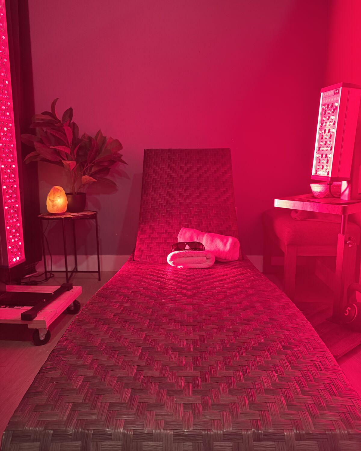 The Red Light Lounge: a woven lounge chair with fresh towels and eye protection between two red-light therapy panels